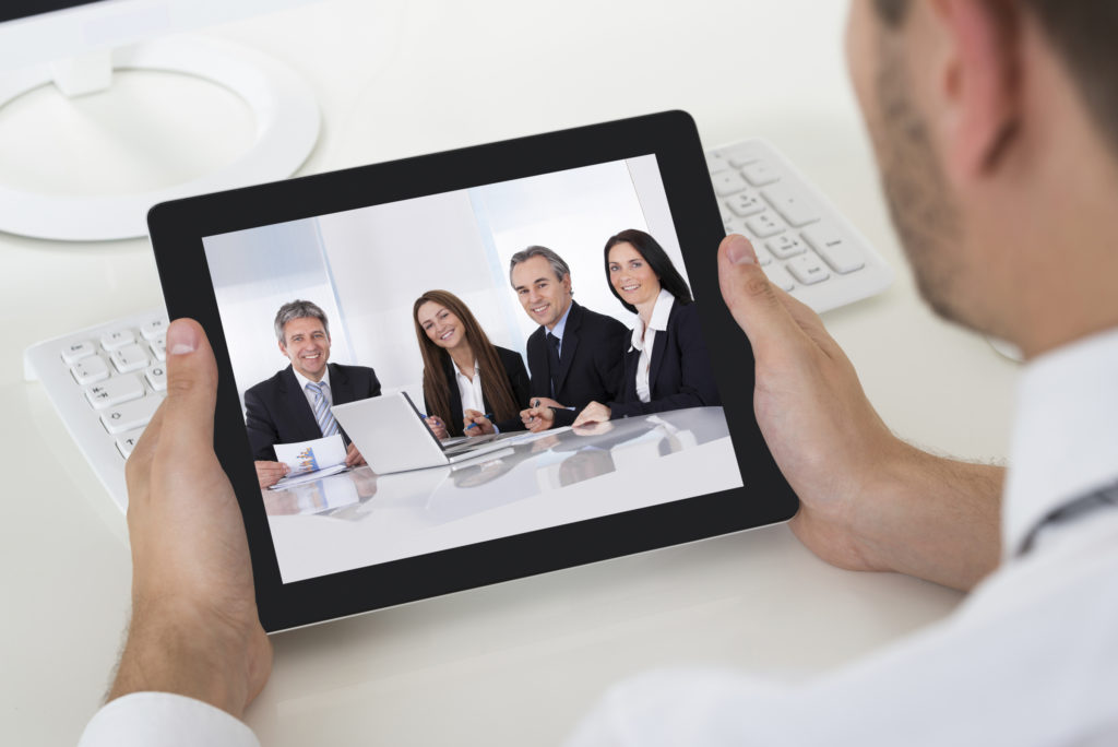 Close-up Of Businessman Videoconferencing With Digital Tablet At Desk